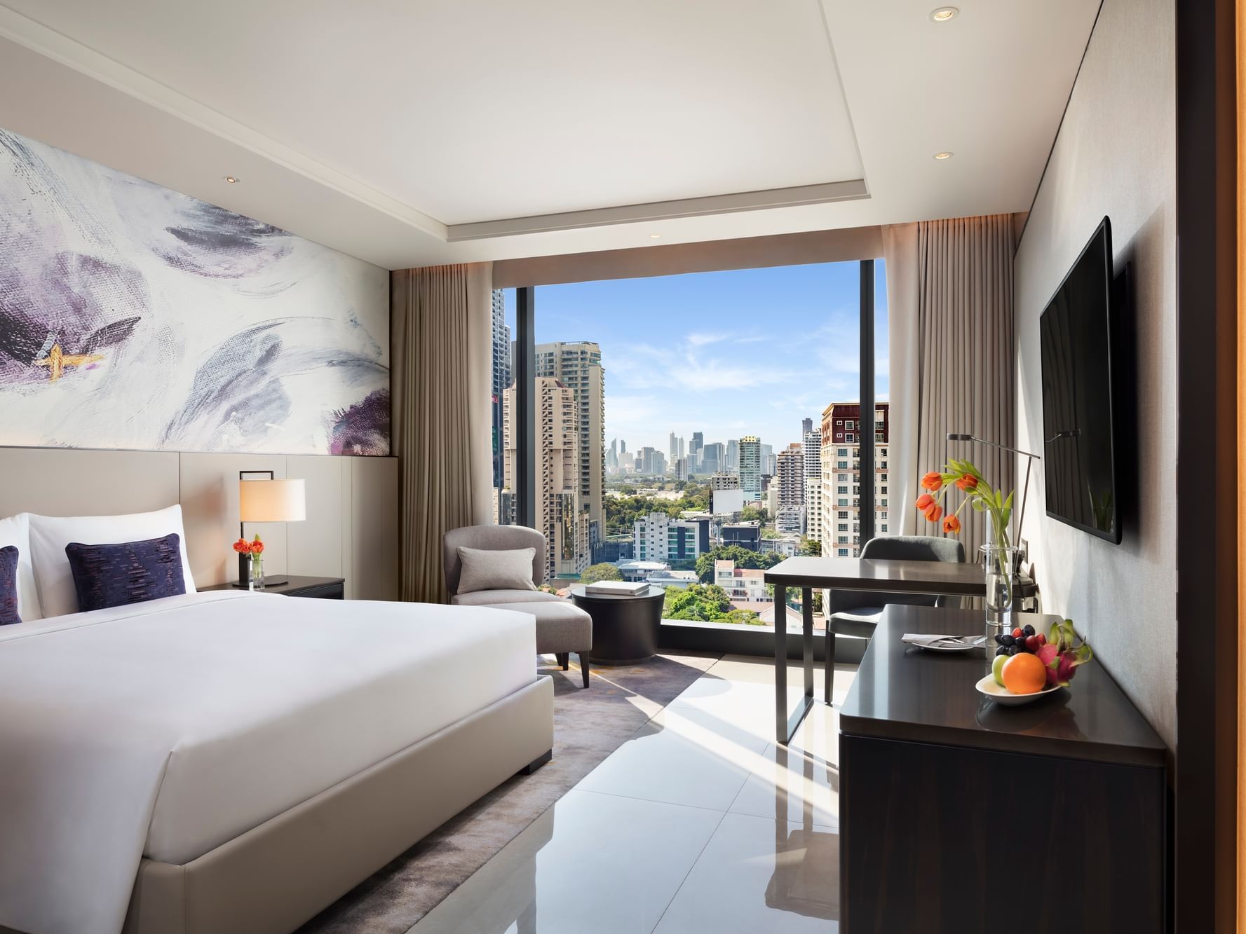Interior of Deluxe Room with a work space & ceiling to floor window overlooking the city at Carlton Hotel Bangkok Sukhumvit