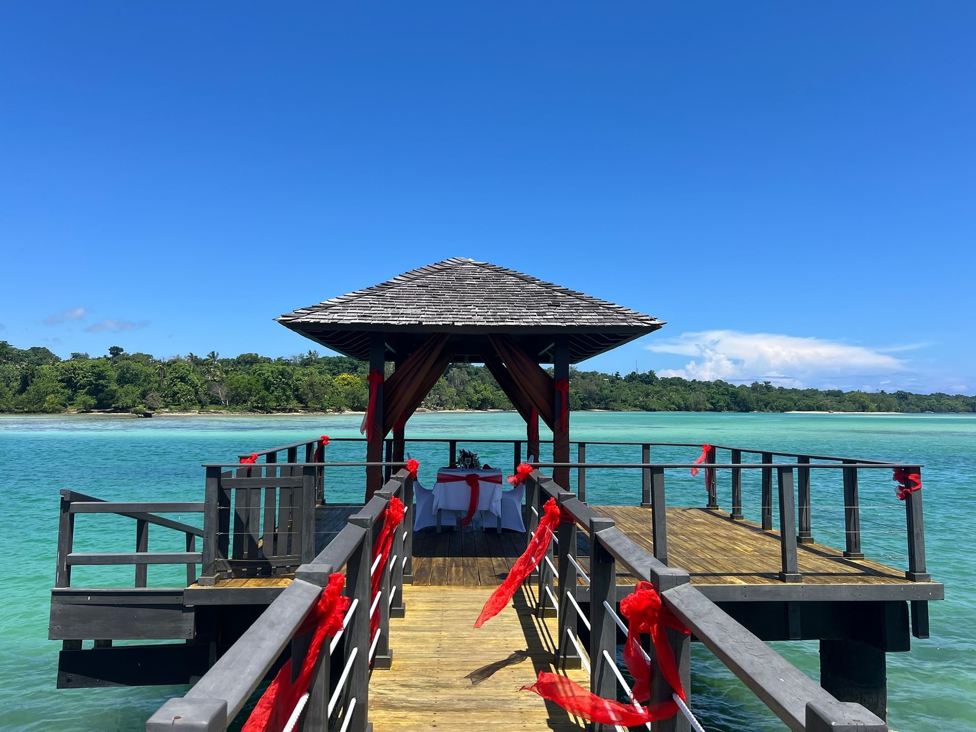Wooden pier with a canopy and decorated table leading to the sea at Warwick Le Lagon - Vanuatu Port Vila
