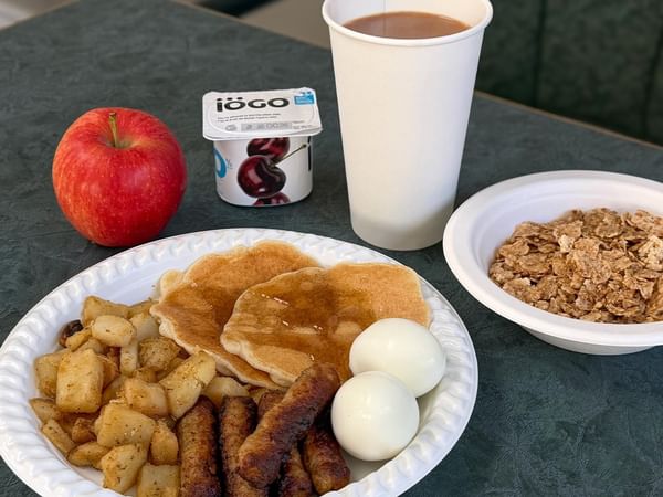Free continental breakfast with pancakes, sausages, eggs, yogurt, apple, cereal and coffee.
