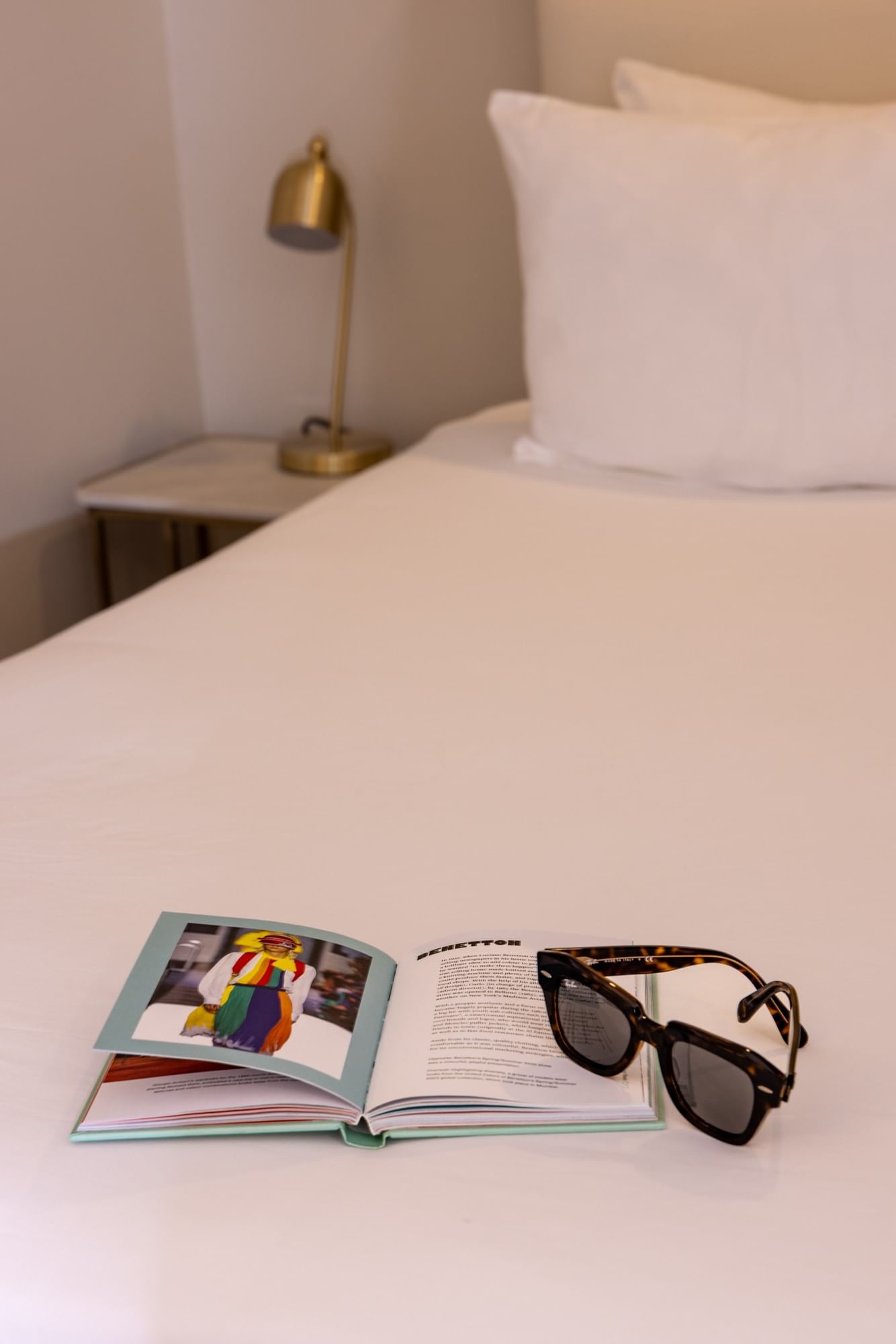A bed with a book and sunglasses on it