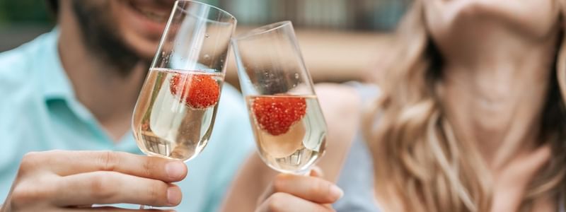 Couple cheering champagne glasses up at Pullman Albert Park