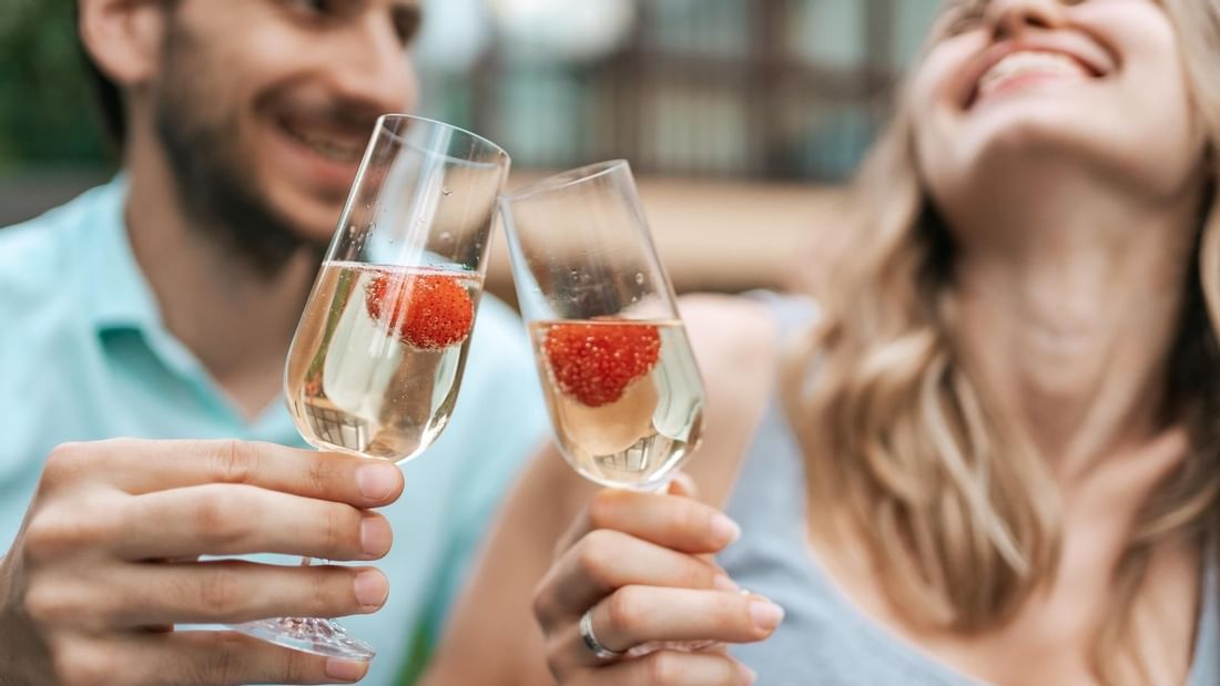 Couple cheering champagne glasses up at Pullman Albert Park