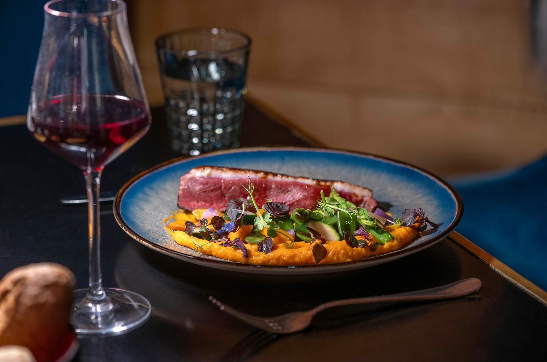 Plated meat dish by red wine under soft lighting served in Restaurant Le W at Saja by Warwick Paris Champs Elysées
