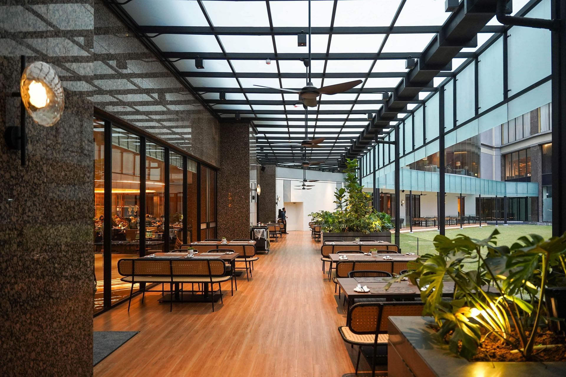 Outdoor dining area with wooden interior next to the garden in Cinnamon Coffee House near One World Hotel