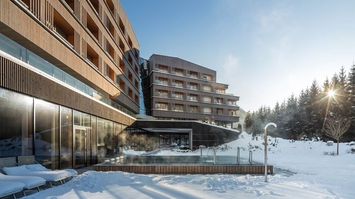 Exterior view of Falkensteiner Hotel Schladming, featuring outdoor pool area in winter