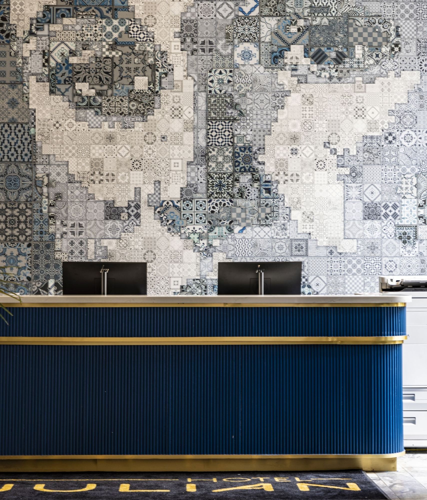 A lobby with a blue and gold reception desk and a mosaic wall