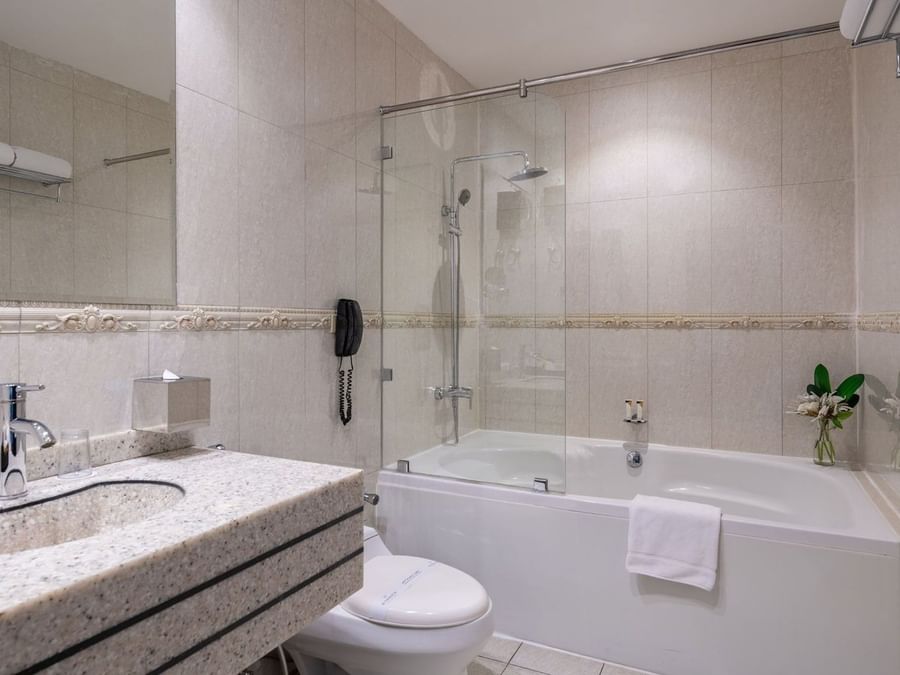 Executive Room Sea View features White bathtub with a glass screen by a granite sink & toilet at Warwick Al Jubail