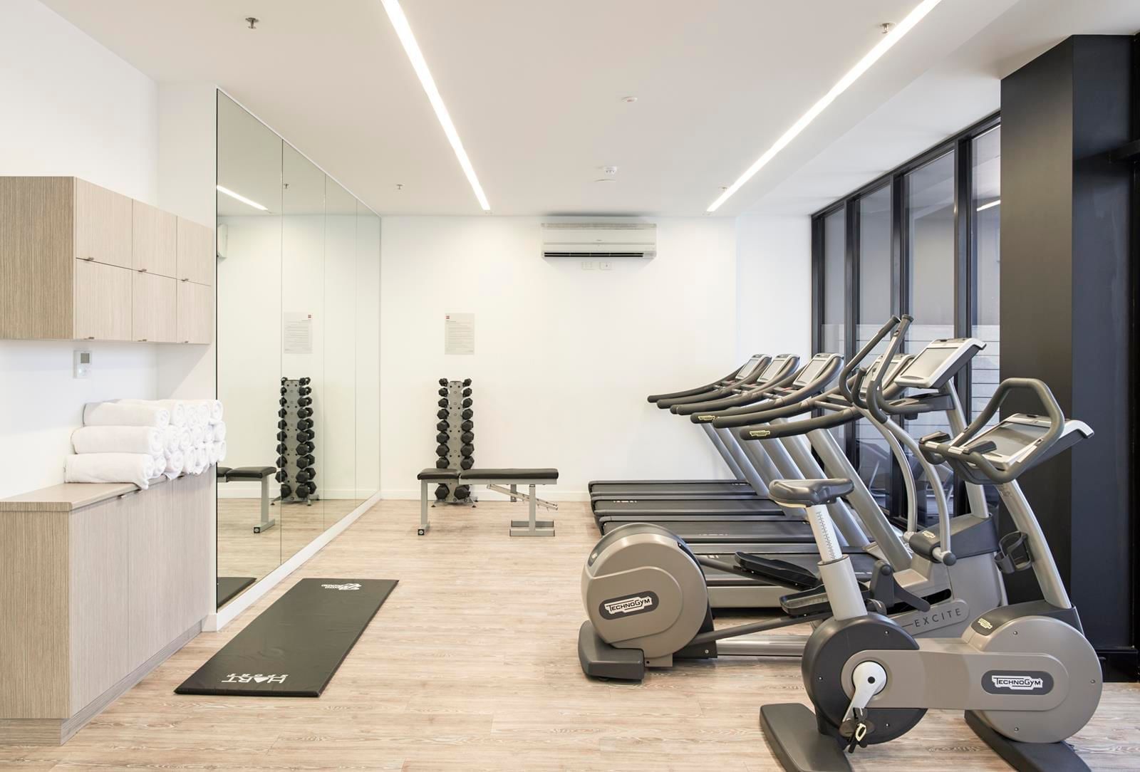 Well-equipped gym featuring treadmills, exercise bikes, weights, and a large mirror at Ibis Adelaide