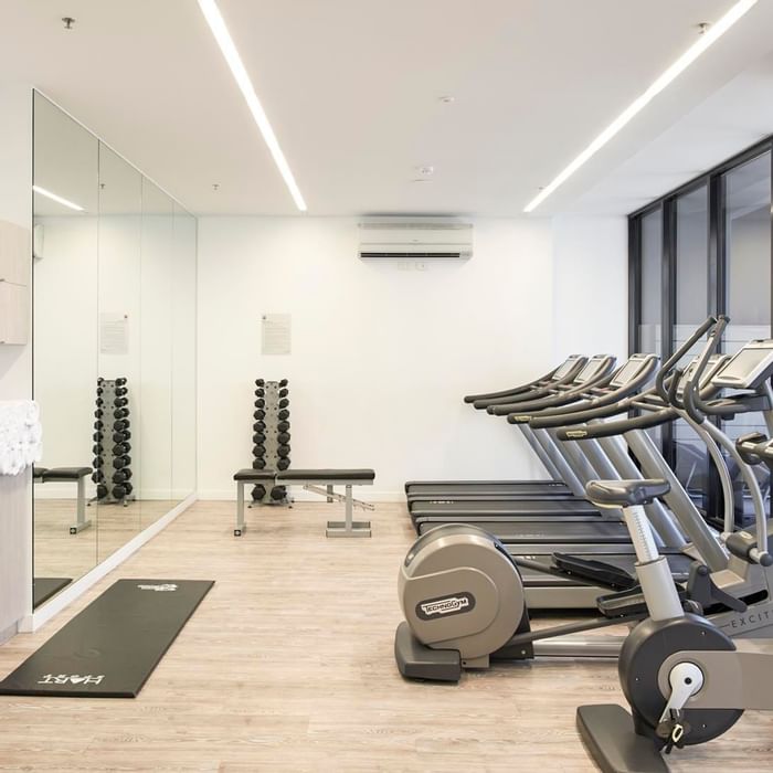 Well-equipped gym featuring treadmills, exercise bikes, weights, and a large mirror at Ibis Adelaide