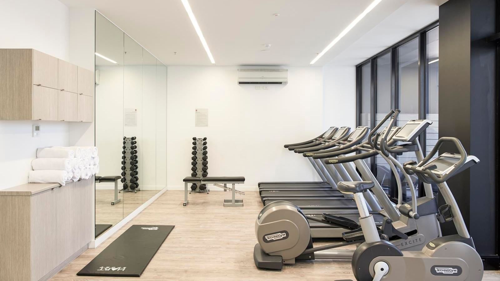 Well-equipped gym featuring treadmills, exercise bikes, weights, and a large mirror at Ibis Adelaide