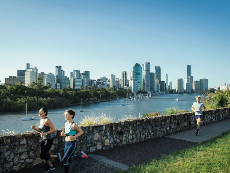 Runners on a pathway with a city skyline and river at Kangaroo Point near Sofitel Brisbane Central