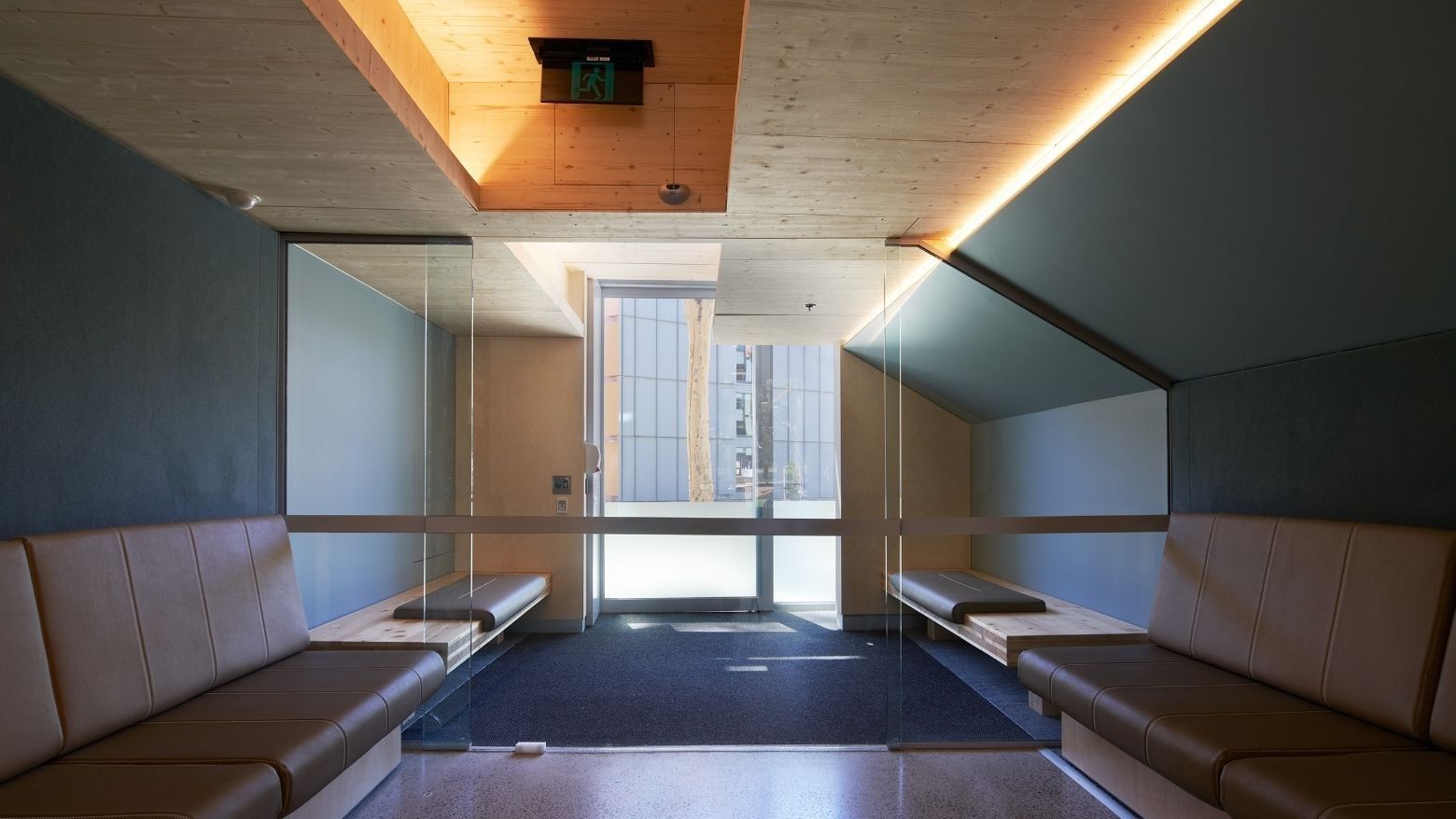Elegant hallway with tan couches and glass doors at La Trobe University North and South Apartments.