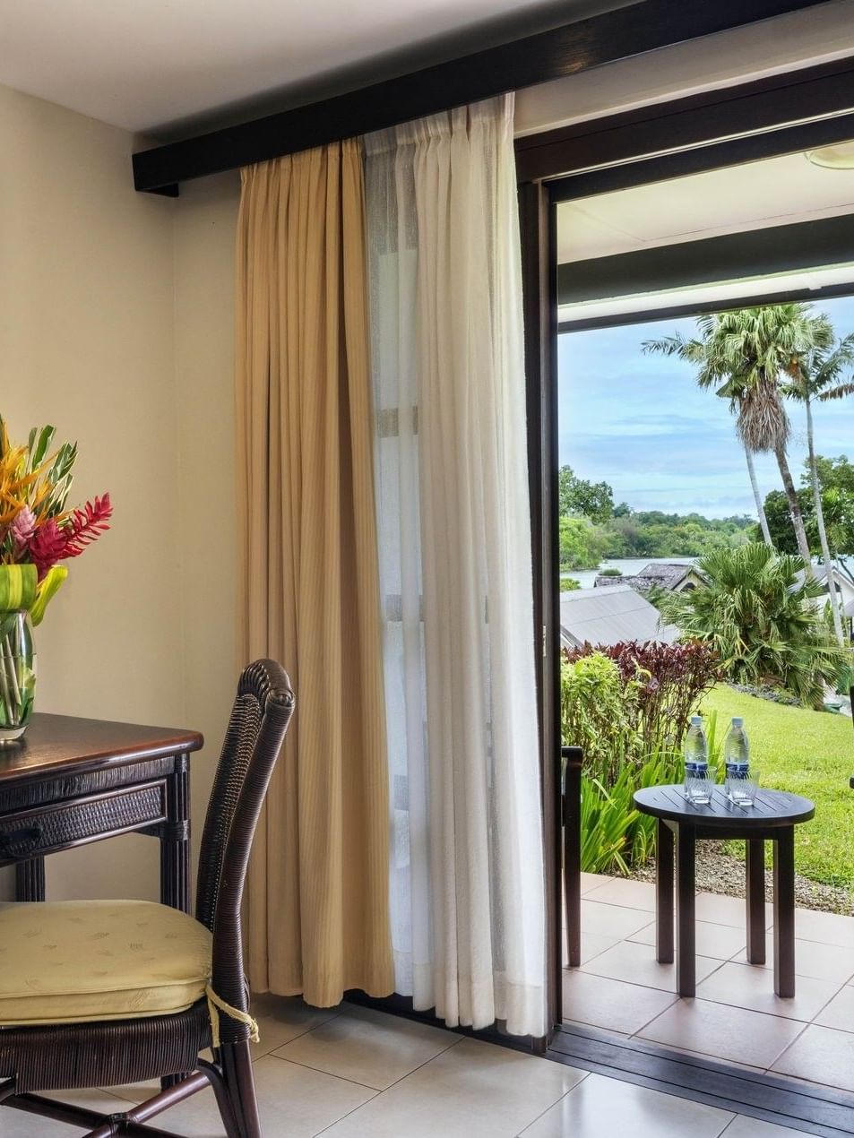 Dark wood vanity desk and flower vase on desk and a glass door leading to a patio at warwick le lagon-vanuatu 