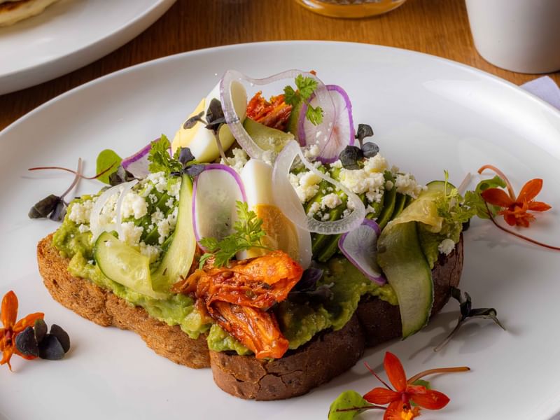 Avocado toast served on a white plate in Palmea Kitchen at The Diplomat Resort