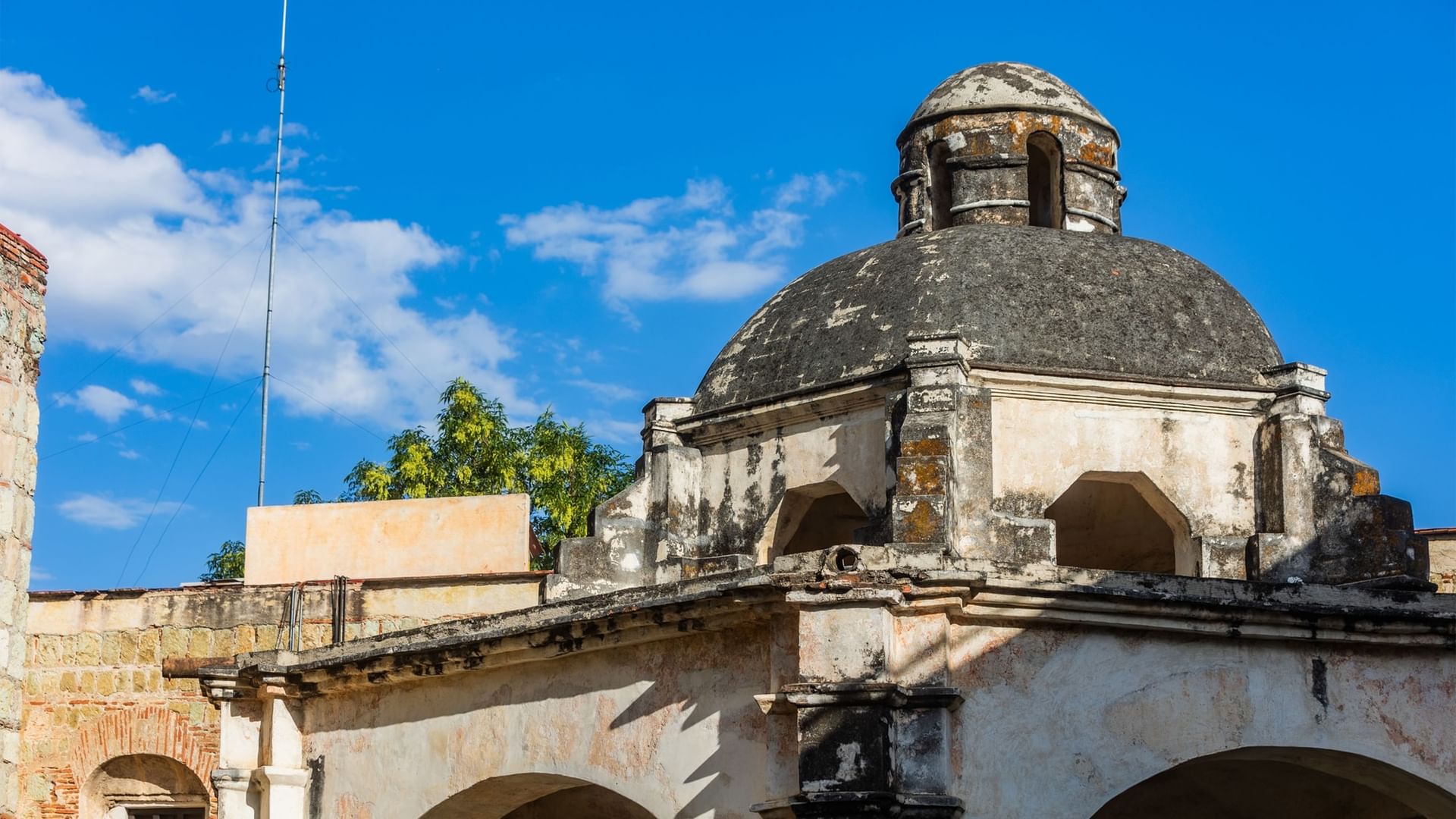 Antigua cúpula de piedra con pequeñas ventanas contra cielo azul brillante en Quinta Real Oaxaca