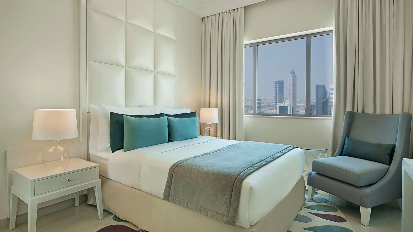 Cozy bed with side tables and chair in Three Bedroom Suite at DAMAC  Maison Dubai Mall Street
