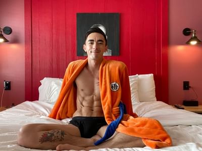 Person in an orange robe relaxes on the bed in the Crate XL room, styled with red walls and soft lighting at The Gaythering