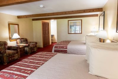 Cozy seating area and nightstand by the bed in The Cottonwoods with wooden beams at The Ranch at UCross