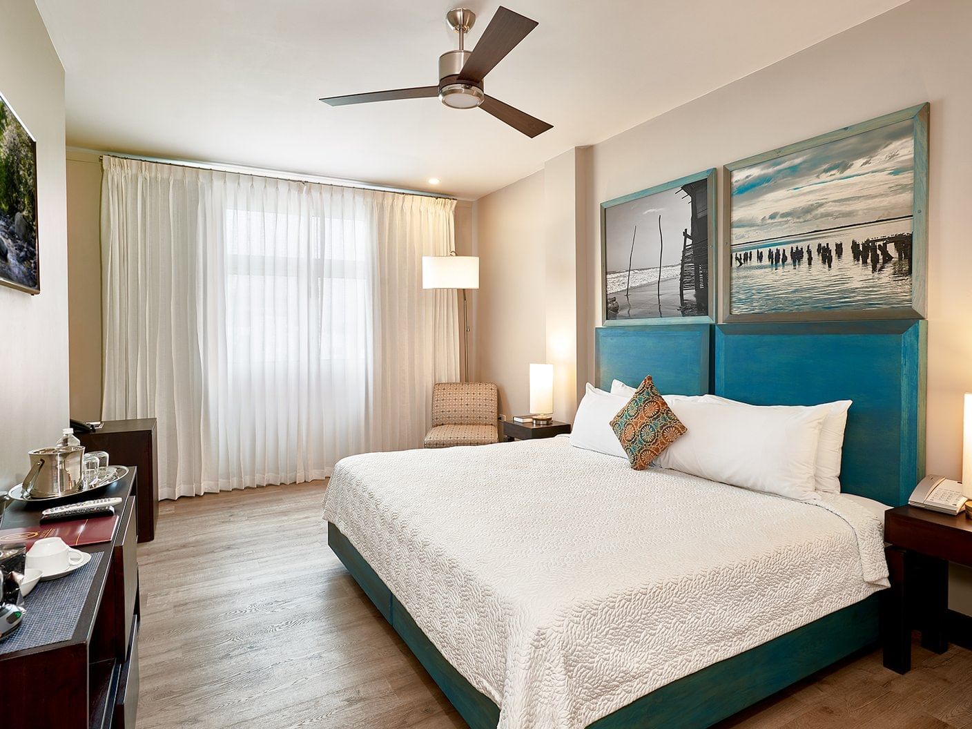 Standard Deluxe Room with teal upholstered bed, ceiling fan, and coastal artwork at R Hotel Kingston.