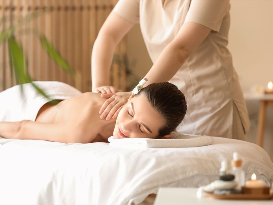 Mujer recibiendo masaje de espalda en la camilla de Kupuri Spa en Guadalajara Plaza Hoteles & Suites