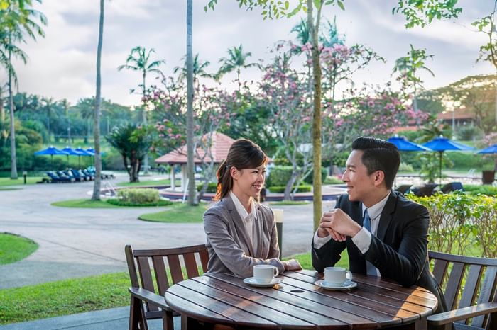 Man and a woman enjoying coffee outdoors amid greenery and flowers at The Saujana Hotel Kuala Lumpur
