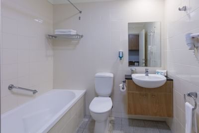 Vanity, lavatory & bathtub in Studio, Nesuto Canberra Apartment