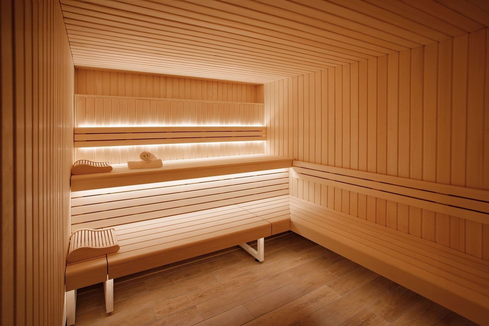 Luxury wood-paneled sauna with tiered seating and ambient lighting at Warwick Reine Astrid - Lyon