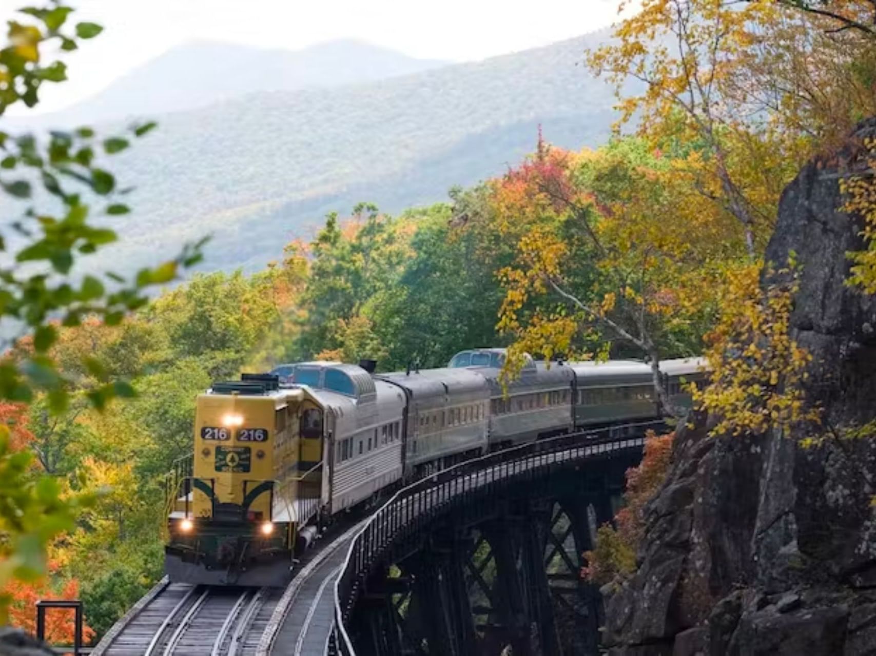 Vintage train chugging along the tracks at Conway Scenic Railroad with stunning mountain views