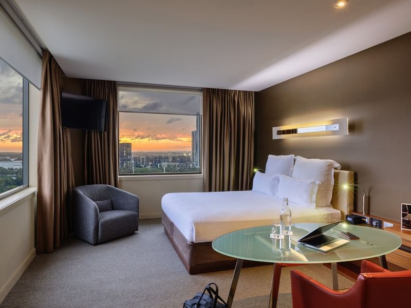 Modern hotel room with a bed, chair, and table at Pullman Sydney Olympic Park.