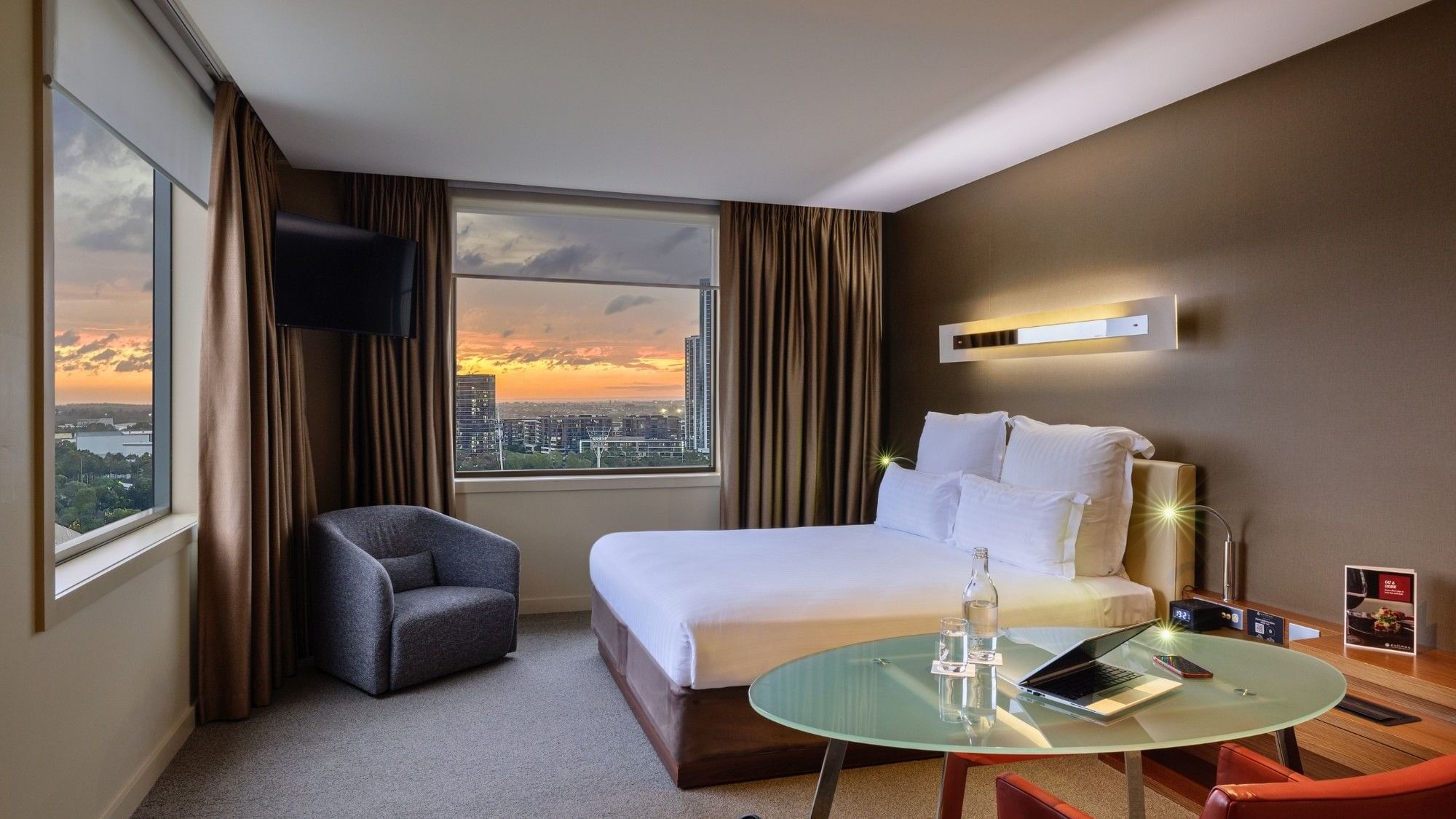Modern hotel room with a bed, chair, and table at Pullman Sydney Olympic Park.