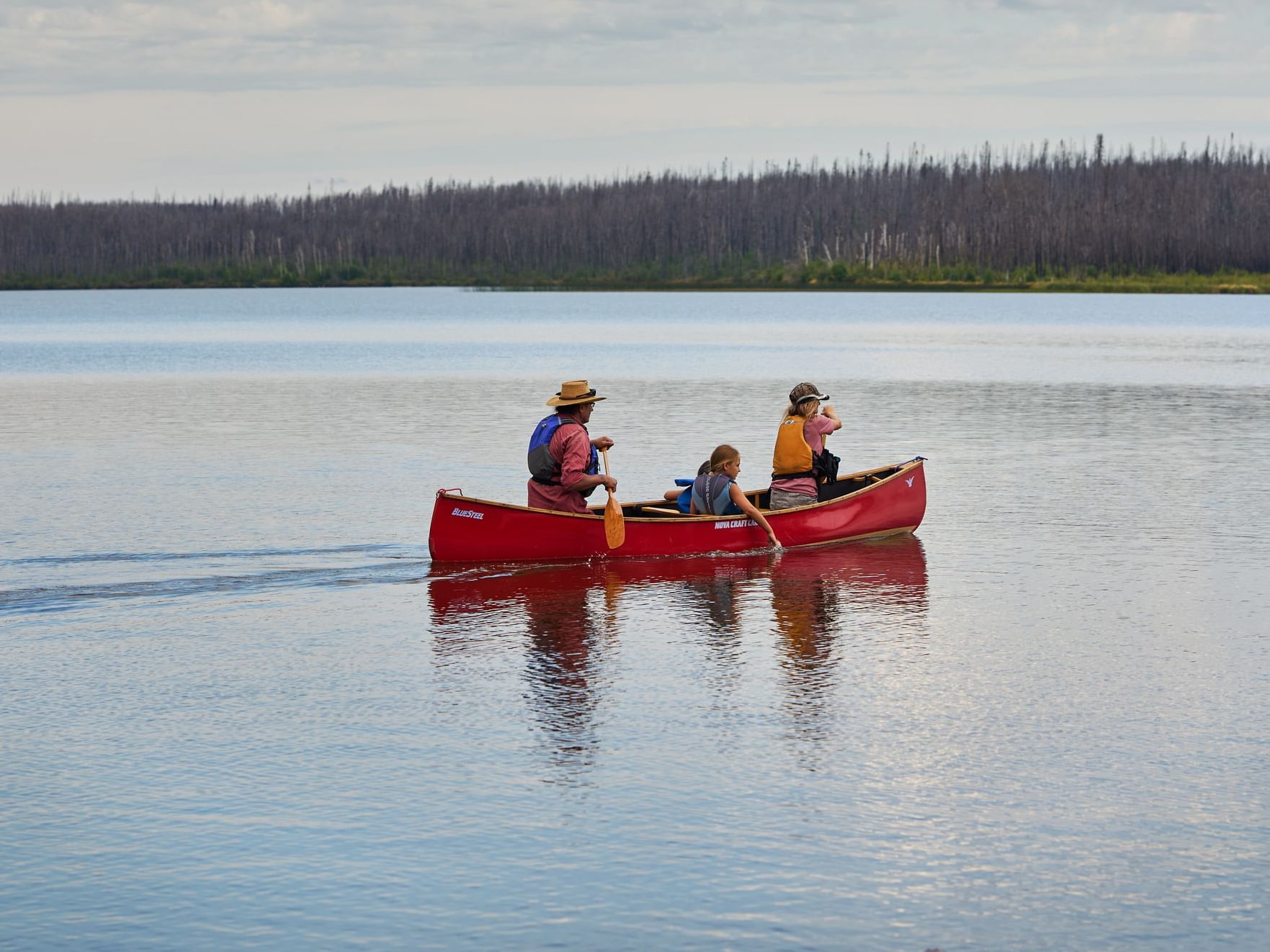 Family canoeing on a serene lake featuring things to do in Fort McMurray near Merit Hotel & Suites