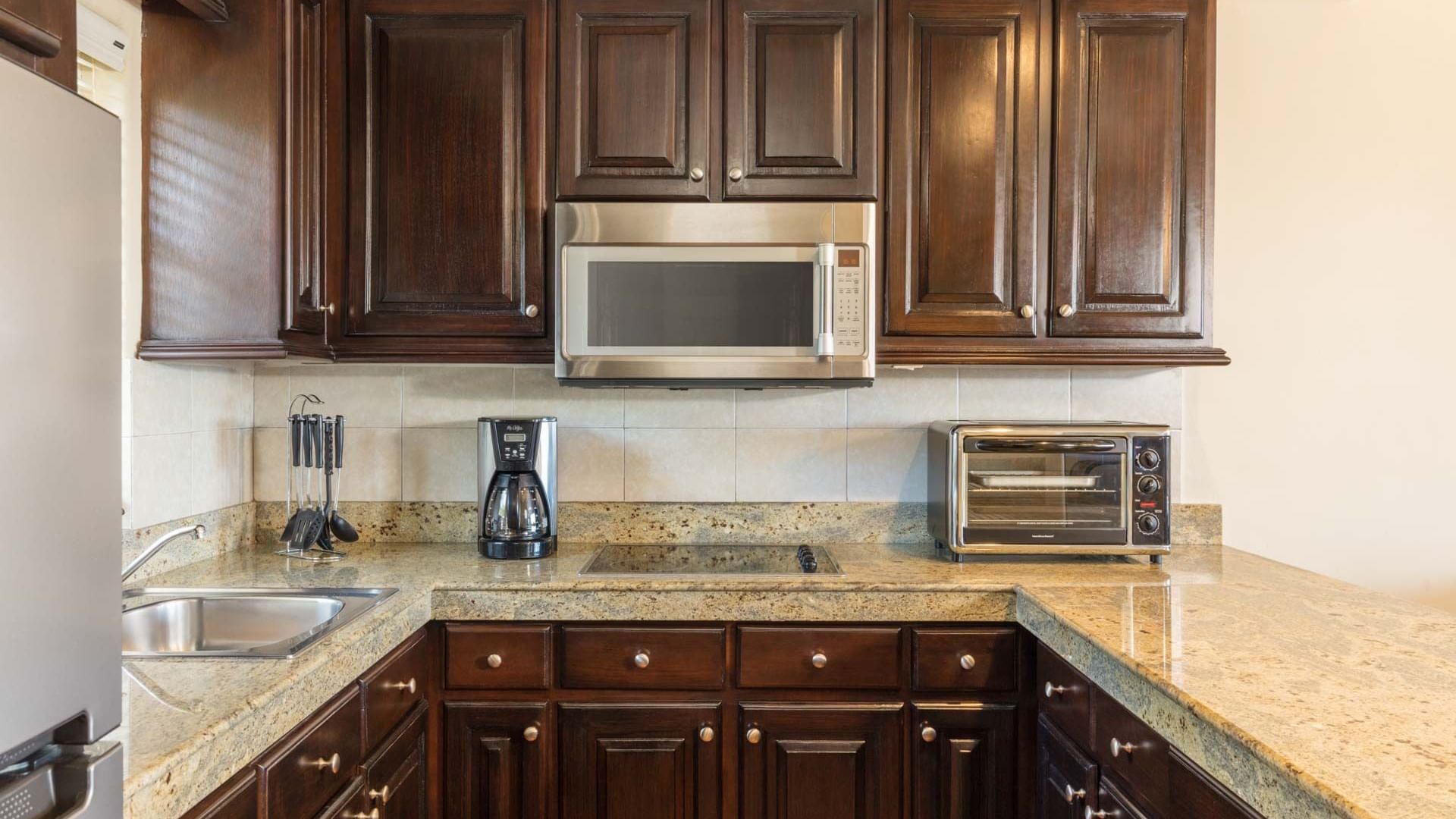 Kitchen with wood cabinets, microwave and coffee maker in the One Bedroom Villa at Hacienda Del Mar Los Cabos.