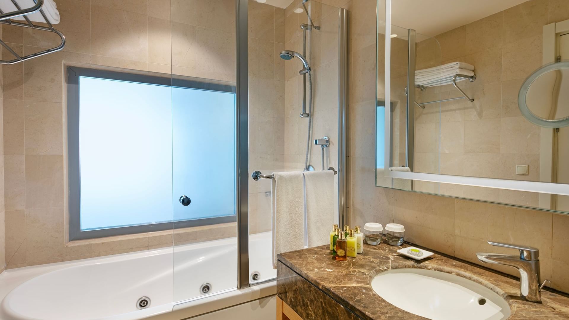 Bathroom features a glass-enclosed bathtub, shower, and marble sink with toiletries in Colonel Suite at Titanic Deluxe Lara