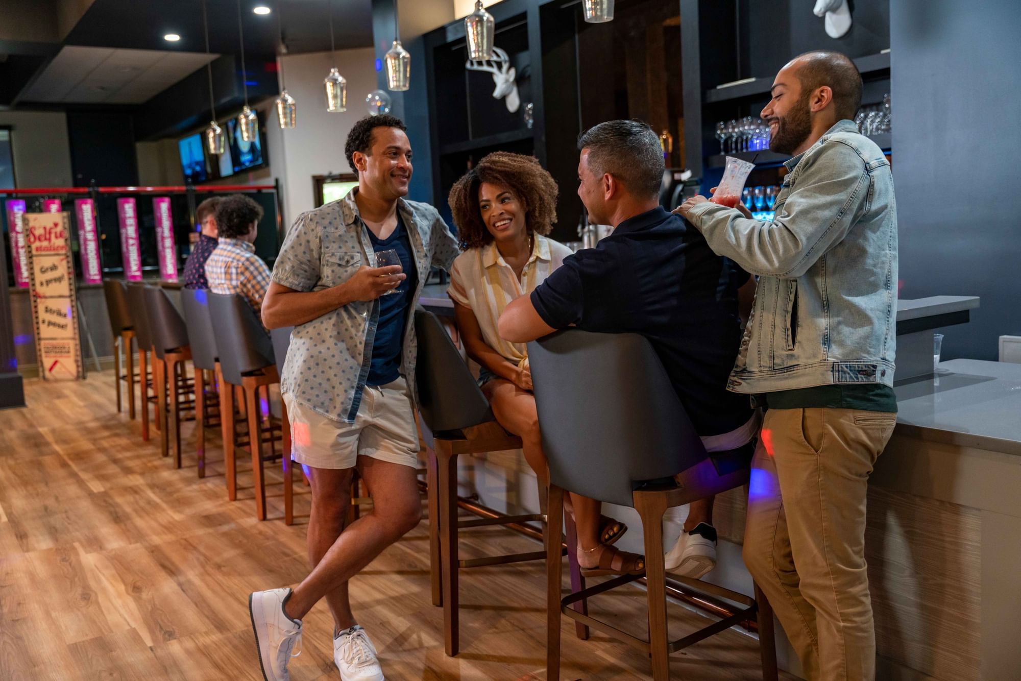 Four friends engage in conversation at the lively Spooners Bar & Grill with stylish decor at Cove Pocono Resorts