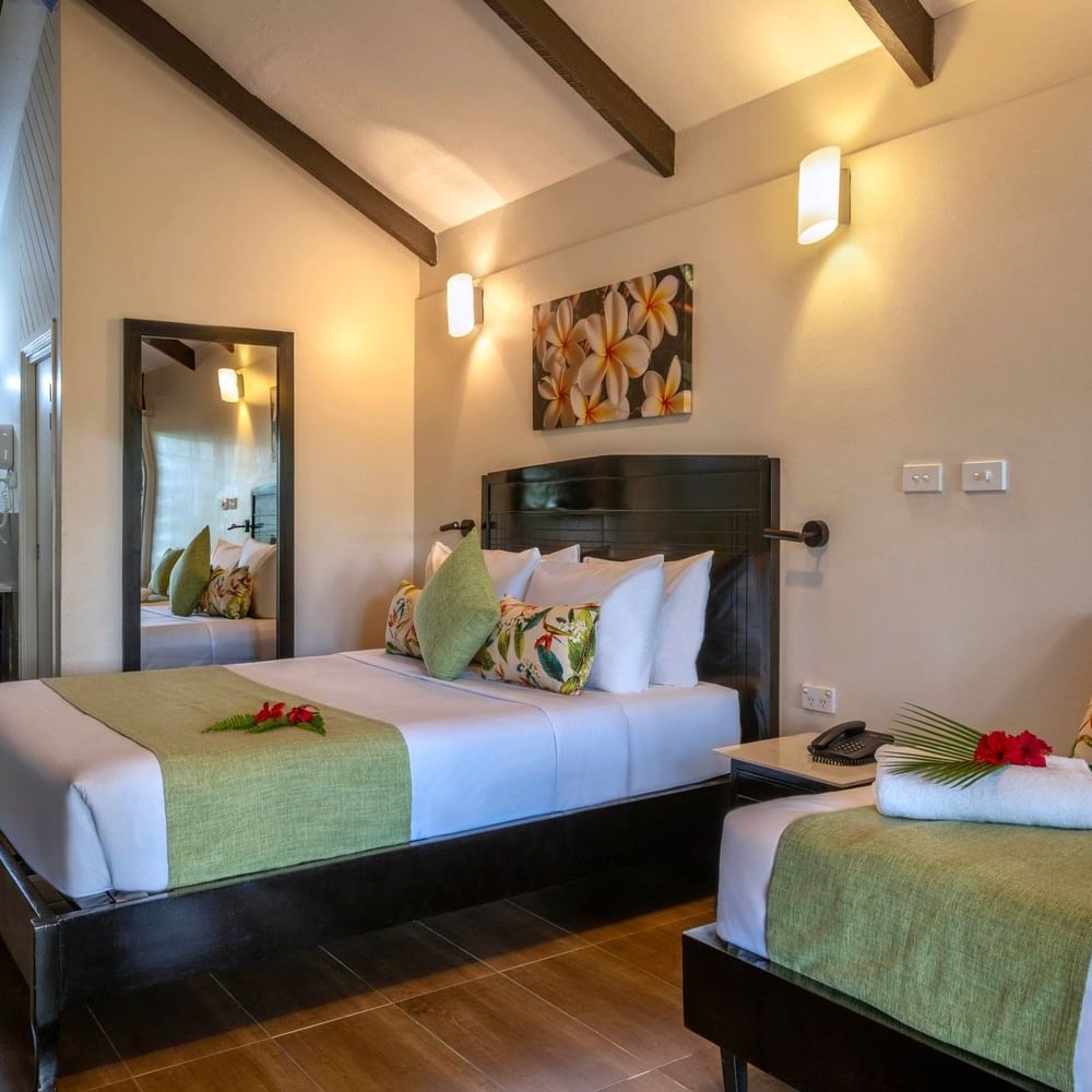Two beds with tropical decor in a Deluxe Villa at Tokatoka Resort in Nadi.