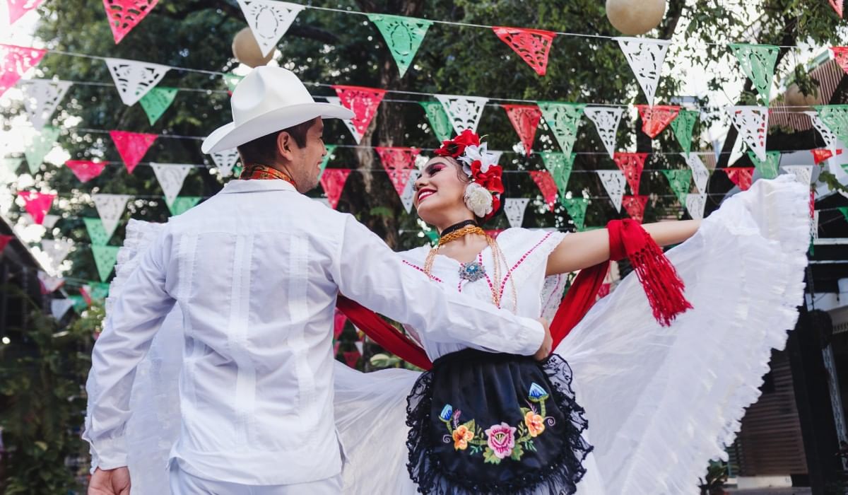 Pareja con vestimenta tradicional blanca bailando cerca de Camino Real Hotels