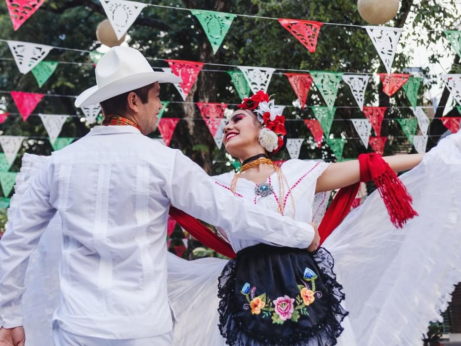 Pareja con vestimenta tradicional blanca realizando un baile cerca de Camino Real Hotels