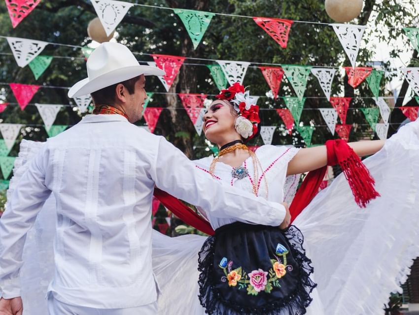 Pareja con vestimenta tradicional blanca realizando un baile cerca de Camino Real Hotels