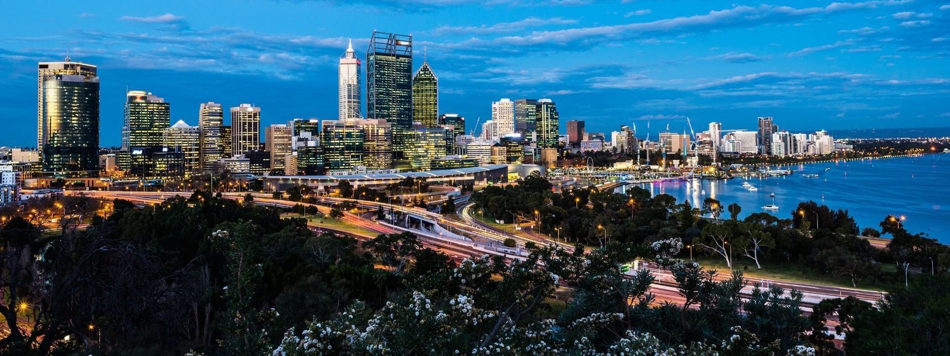 Striking Novotel Perth Langley city skyline view at dusk with illuminated skyscrapers and the winding freeway below
