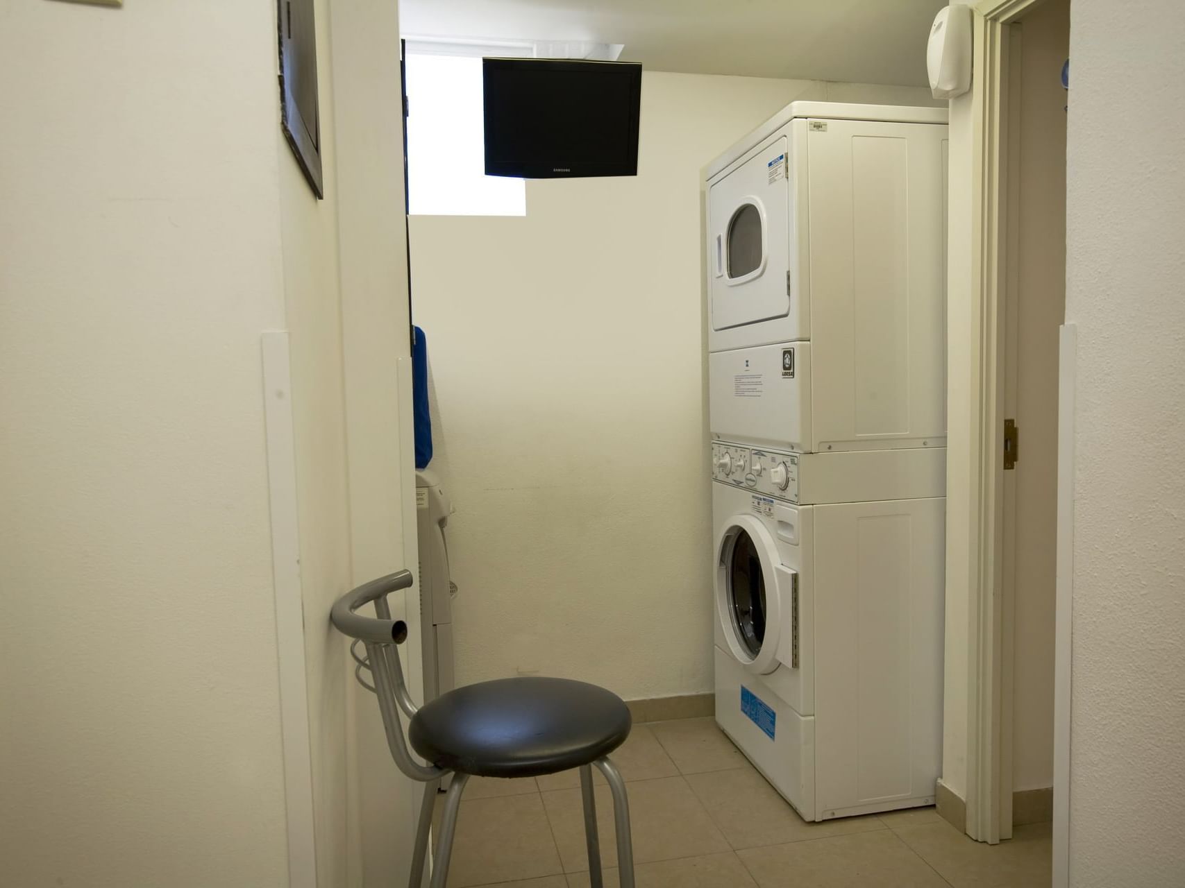 A chair by a washing machine in a laundry room at One Hotels