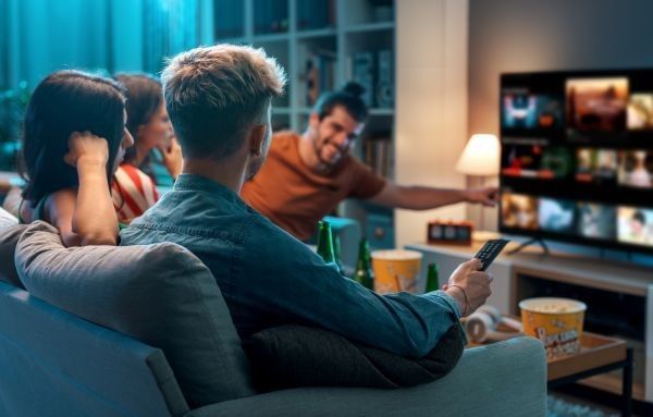 Friends choosing a movie to watch together at home, video on demand concept.