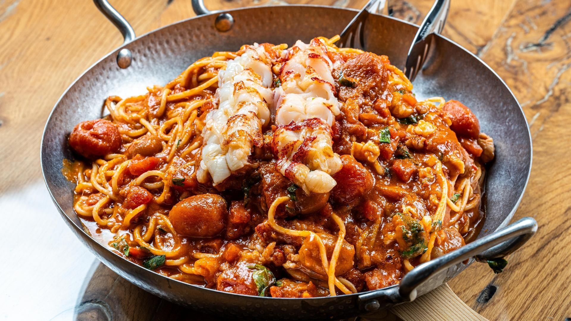 Rich seafood spaghetti dish with fresh lobster pieces served in a metal wok pan at Falkensteiner Hotel & Spa Jesolo