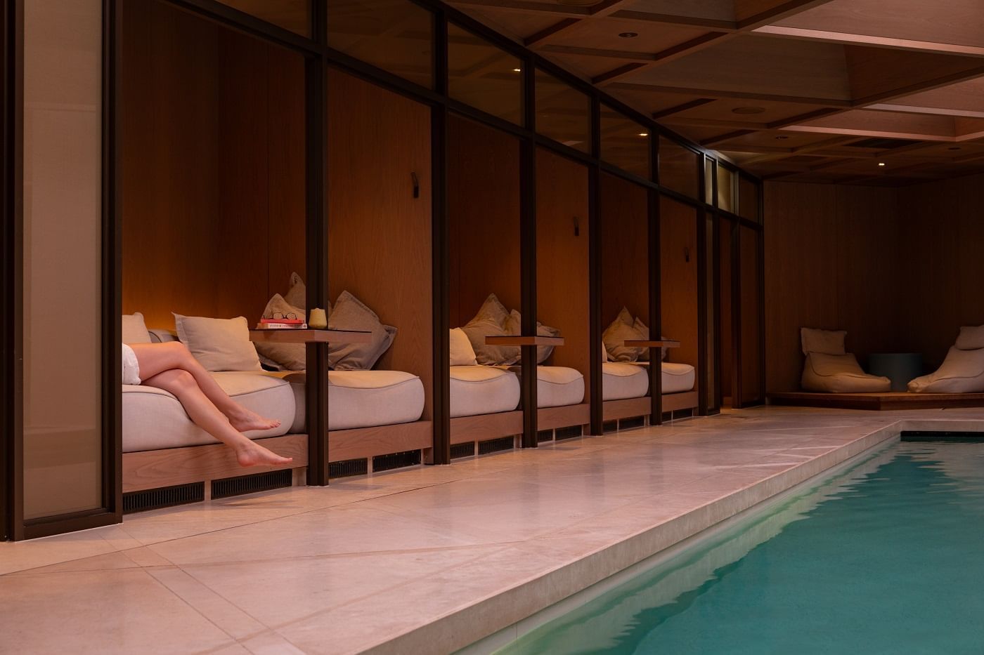 People relaxing on the comfy beds by the indoor pool at The Londoner