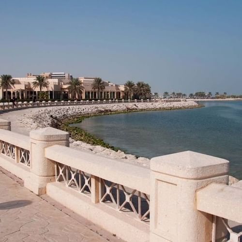 Al Khobar Corniche by a white railing under a clear sky near a coastal resort building near Naviti by Warwick Al Khobar