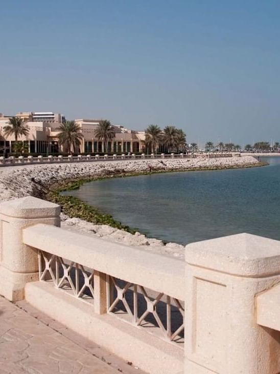 Al Khobar Corniche by a white railing under a clear sky near a coastal resort building near Naviti by Warwick Al Khobar