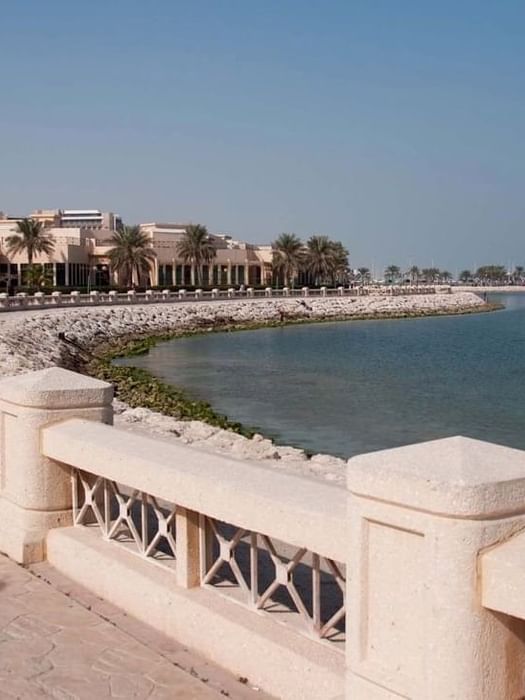 Al Khobar Corniche by a white railing under a clear sky near a coastal resort building near Naviti by Warwick Al Khobar