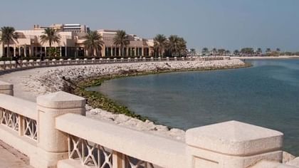 Al Khobar Corniche by a white railing under a clear sky near a coastal resort building near Naviti by Warwick Al Khobar