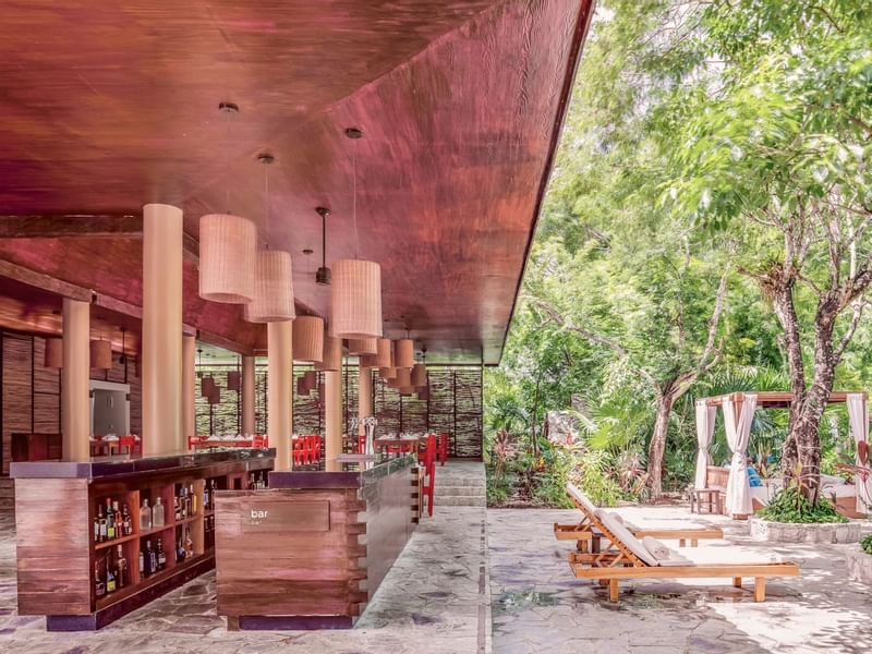 Bar shelves & outdoor loungers by a cozy restaurant at The Explorean Cozumel