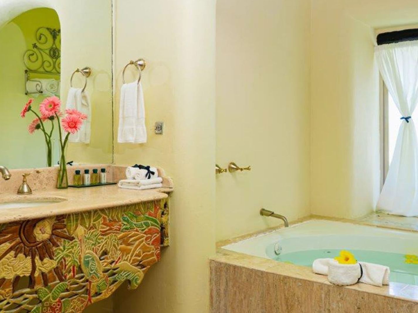 King Grand Class Suite bathroom featuring a large soaking tub and a colorful carved vanity  at Quinta Real Huatulco