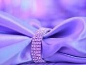 Close-up of a decorative purple satin bow with a sparkling diamante clasp, bathed in soft lighting at The Sebel Brisbane